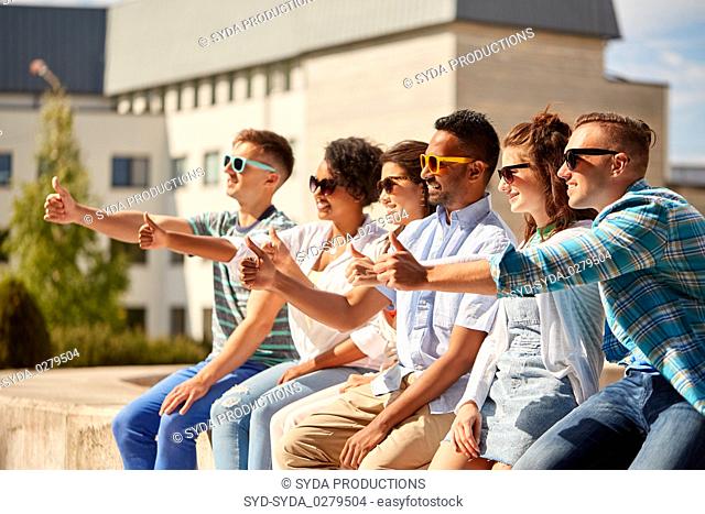 friends in sunglasses showing thumbs up in city