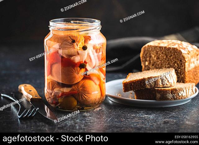 Pickled sausages with onion and red pepper. Marinated food in jar