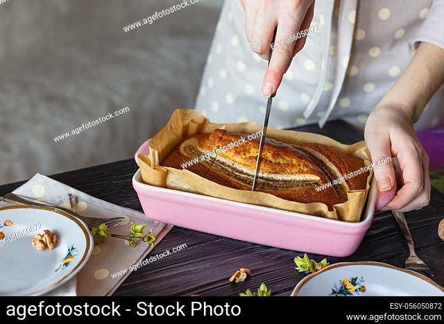 The baker cuts a banana cake. Close-up view girls hands with knife