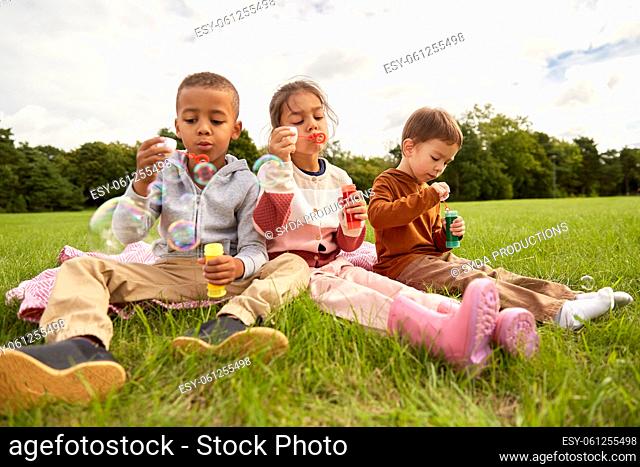 group of children blowing soap bubbles at park