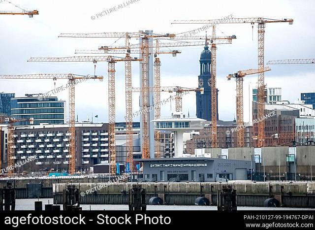 03 January 2021, Hamburg: The tower of Hamburg's main church St. Michaelis, the Michel, can be seen through the cranes of the Ìberseequartier construction site