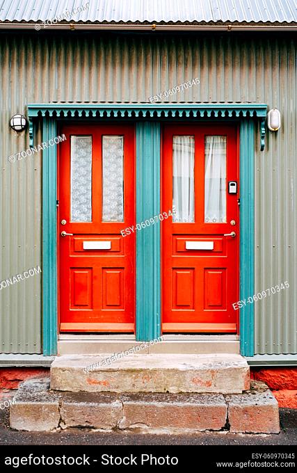 Two orange entrance doors with glass and curtains in a blue doorway. High quality photo