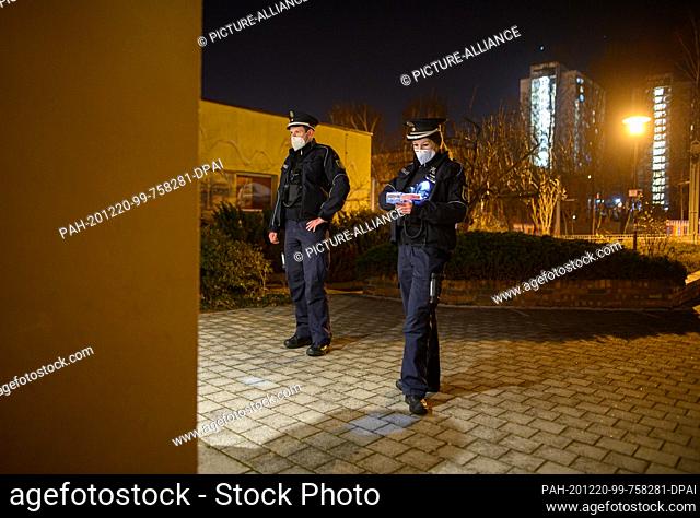 19 December 2020, Saxony, Dresden: Police officers check identification documents as part of a curfew check in the Gorbitz district during the night
