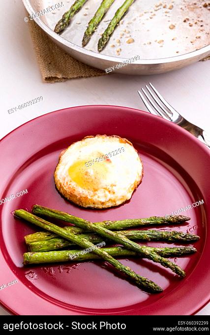 fried green healthy asparagus with egg on red plate