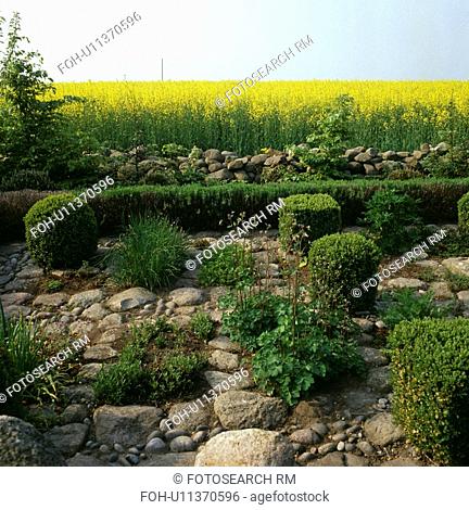Clipped shrubs and large stones in small country garden in summer