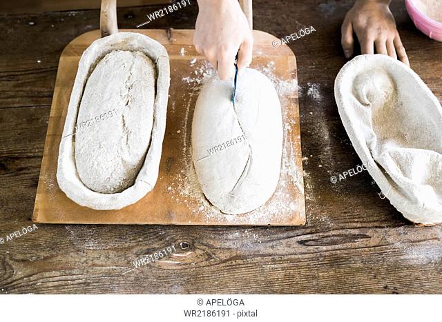 High angle view of baker's hands making design on dough at table in bakery