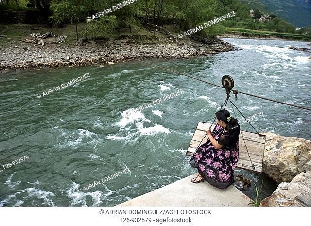Woman crossing a river by traditional way in Damba, Sichuan Province