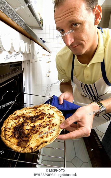 man getting sceptically a burnt Tarte flamb?e out the oven