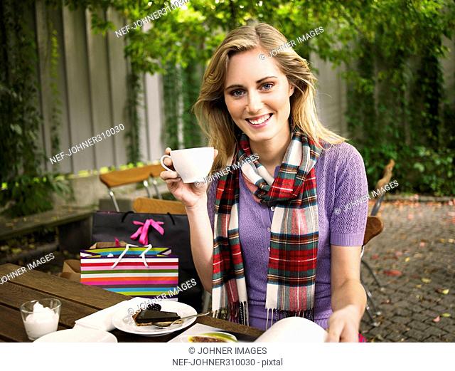 A smiling young woman in a cafe outside