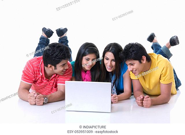 Happy friends using laptop against white background