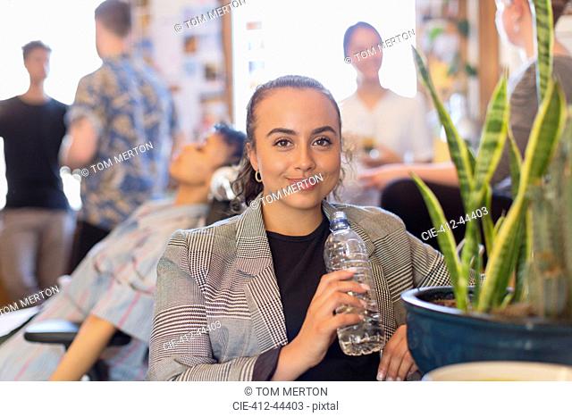 Portrait confident businesswoman drinking bottled water in office