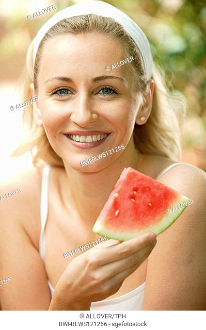 woman eating melon in the garden, portrait