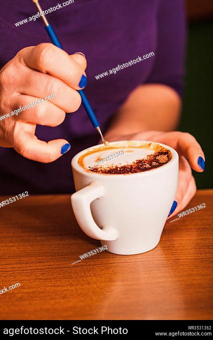 Barista is show how to make latte art coffee. Lesson with special metal device - latte-art pen tool