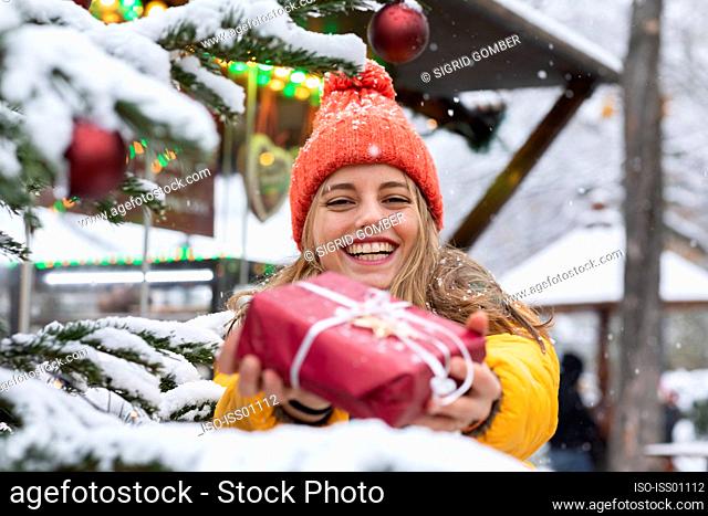 Smiling young woman holding Christmas present outdoors