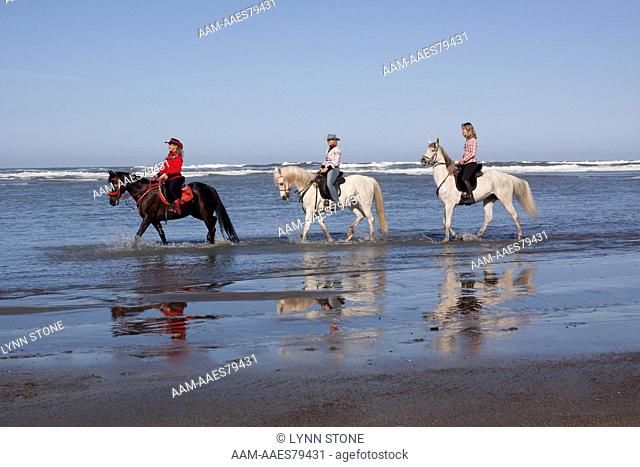 Three lady riders along surf edge; Northern California, USA (Released)