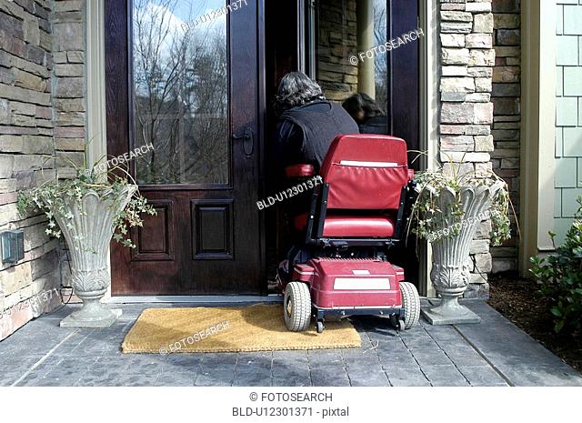 A woman using a wheelchair enters her home