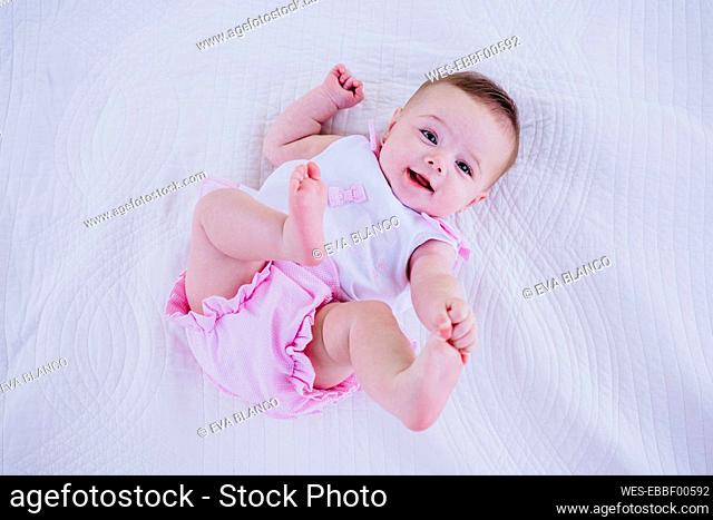 Baby girl touching toes while lying on blanket