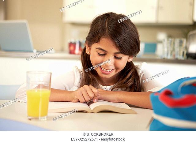 Hispanic Girl With Reading Homework At Table