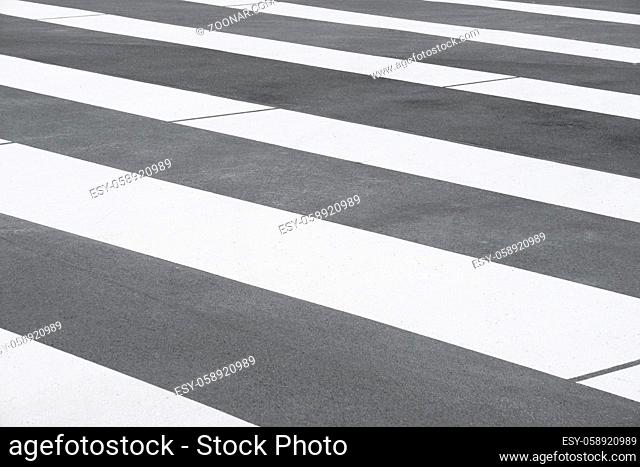 close-up zebra crossing or crosswalk background - abstract pattern with white stripes on gray asphalt
