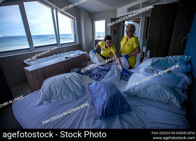 18 March 2020, Mecklenburg-Western Pomerania, Ahlbeck: Asmara Altea (l) and Silke Jubel (r) pull the laundry from a guest bed in the hotel ""Das Ahlbeck"" after...