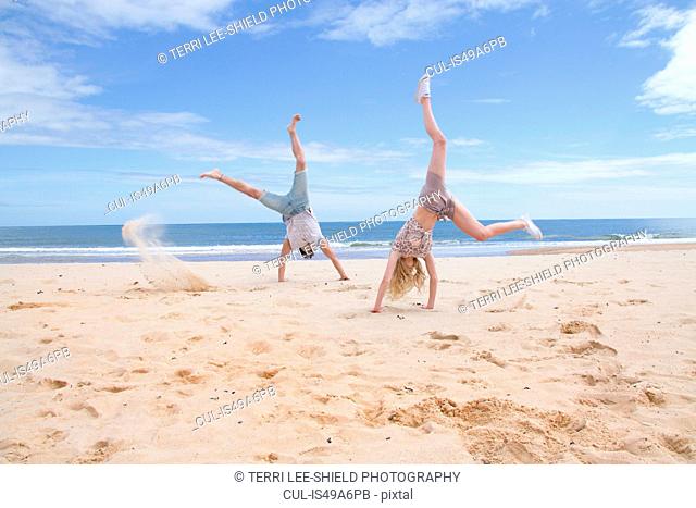Young couple doing handstands on beach