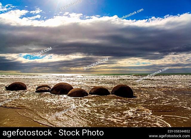 Moeraki boulders. Ocean tide begins. Group of large round boulders on the coast of the South Island of New Zealand. Sunset