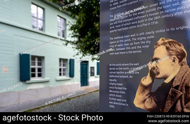 PRODUCTION - 09 August 2023, Saxony-Anhalt, Naumburg: A stele with a portrait of Friedrich Nietzsche in front of the Nietzsche House in Naumburg provides...
