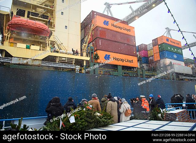 08 December 2023, Hamburg: A Christmas tree is delivered by crane to seafarers on a container ship from the deck of a Rainer Abicht excursion ship during the...