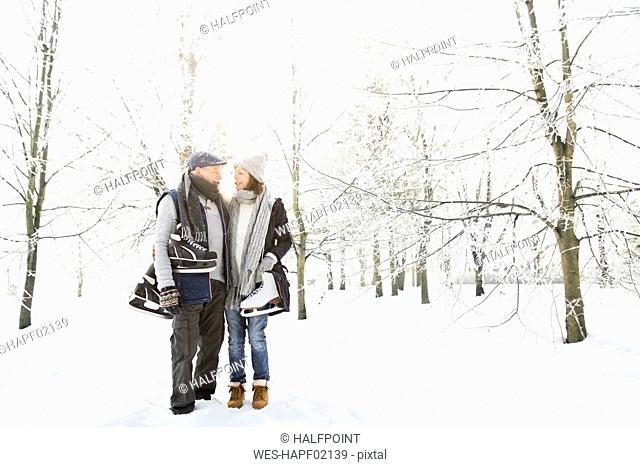 Senior couple with ice skates in winter forest