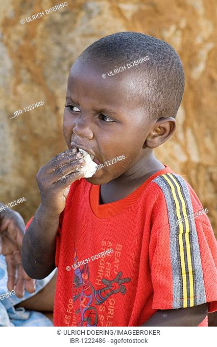 African boy eats maize porridge with one hand, Magoye, Mazabuka, Zambia, Africa