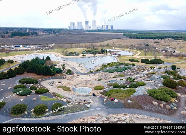 15 March 2023, Saxony, Boxberg: Gardeners work in the Nochten erratic block park in the landscaped garden against the backdrop of the Boxberg lignite-fired...