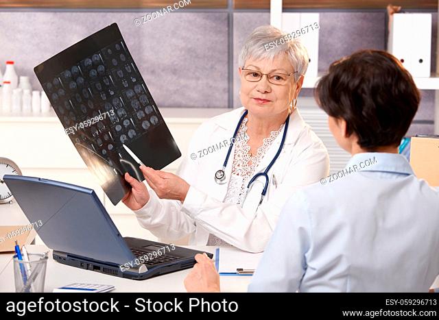 Senior doctor showing x-ray results to patient in office