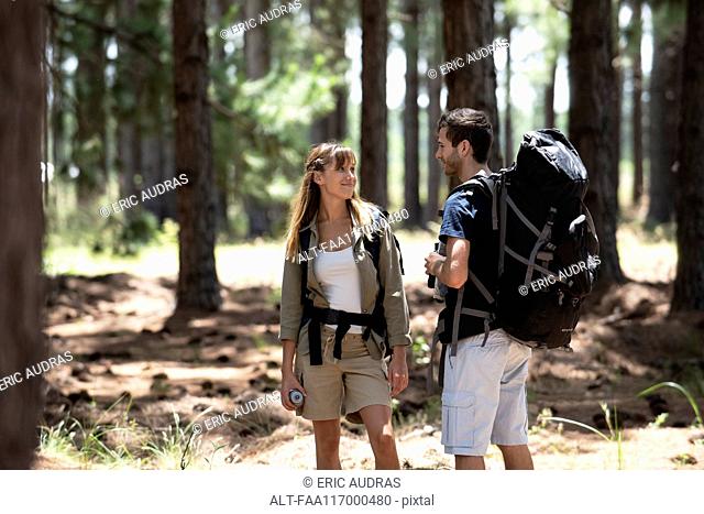 Smiling young couple standing in pine forest
