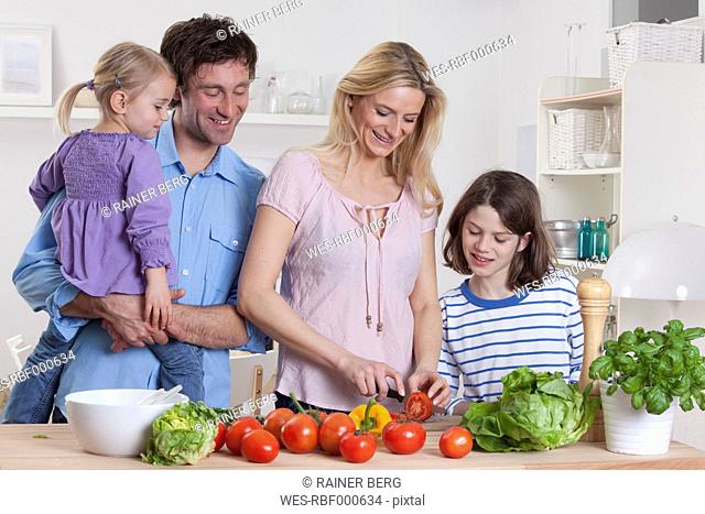Germany, Bavaria, Munich, Mother preparing salad with son, father and daughter standing besides them