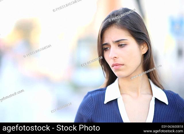 Sad woman complaining looking down walking in the street