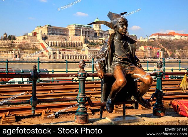 Budapest, Hungary, March 22 2018: Statue of a sitting child with a hat near the tram rail on the banks of the Danube