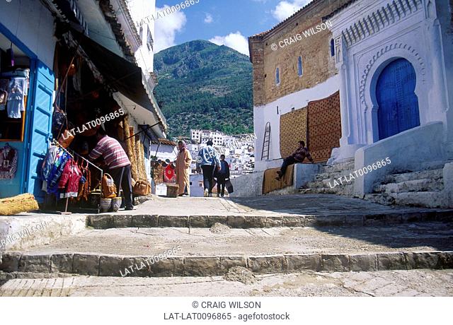 Rif mountain village. Stepped cobbled street. White washed house walls. Blue door. People. Shop