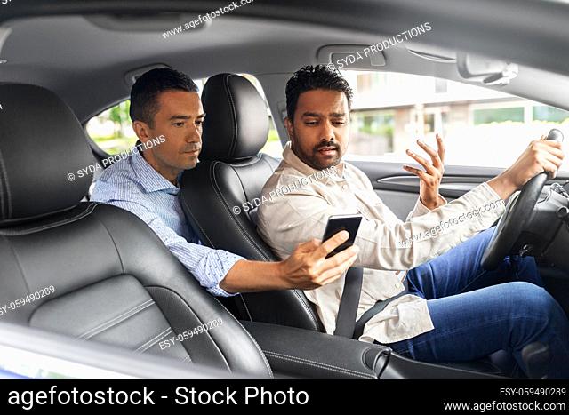 male passenger showing smartphone to car driver