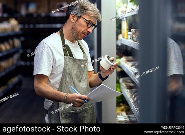 Store owner examining container working in organic market