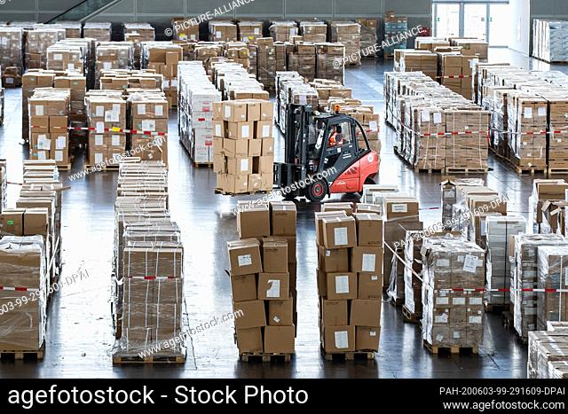03 June 2020, North Rhine-Westphalia, Duesseldorf: A forklift truck carrying numerous boxes with protective equipment passes through a warehouse