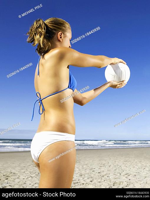 Young woman preparing to serve volley ball to team members at the beach