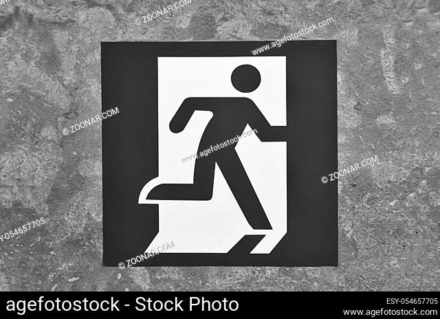 Pointer on the wall indicating the direction of movement to the exit of the room. Black and white image