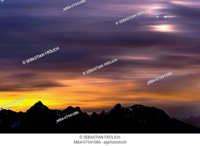 Colorful night photography of the Karwendel mountains with blurred clouds and crescent moon