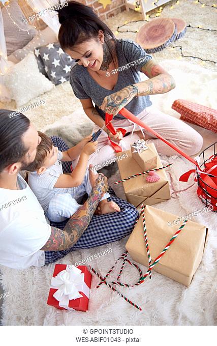Boy opening Christmas present with his parents in bed