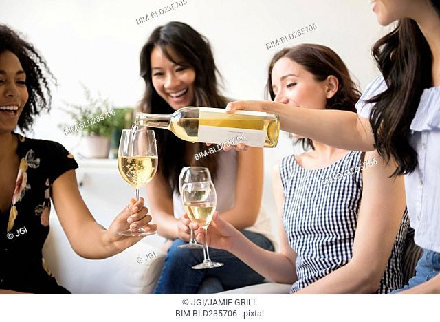 Woman pouring bottle of white wine for friends