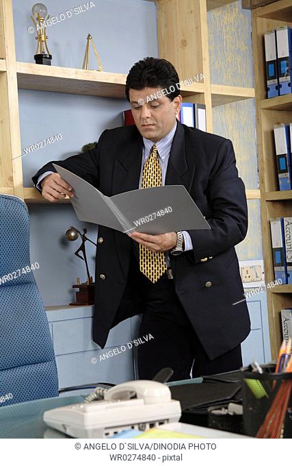 Executive holding file in both hand looking and reading it standing in cabin MR 687U