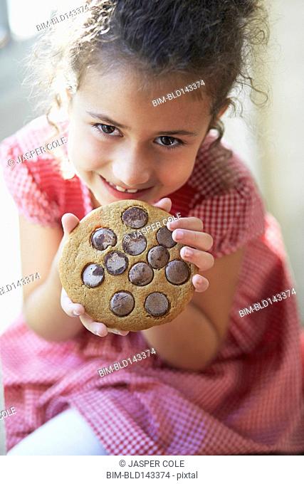 Mixed race girl eating large cookie