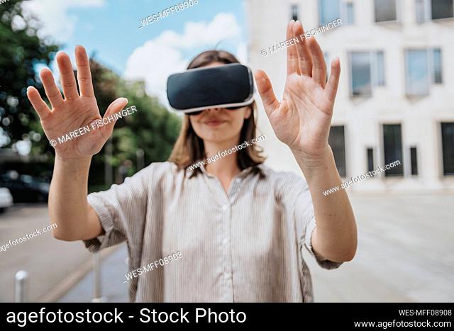 Woman gesturing wearing virtual reality headset at street
