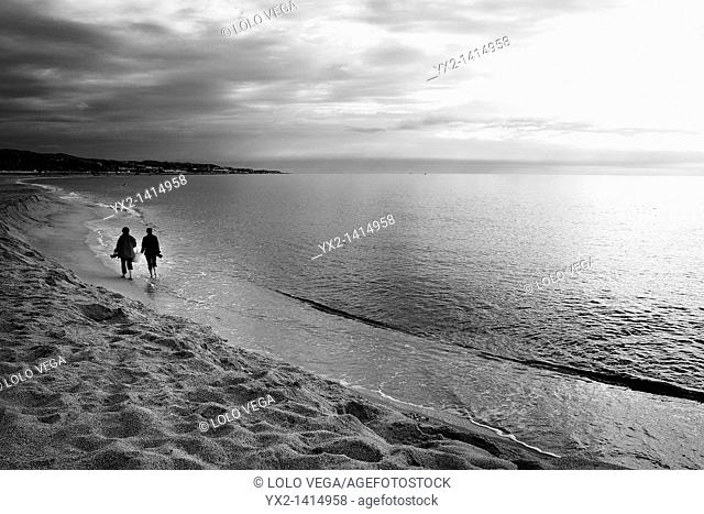 Couple walking on beach, Mataro, Catalonia, Spain