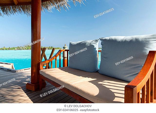 travel, tourism, vacation and summer holidays concept - patio or terrace with canopy and bench on beach